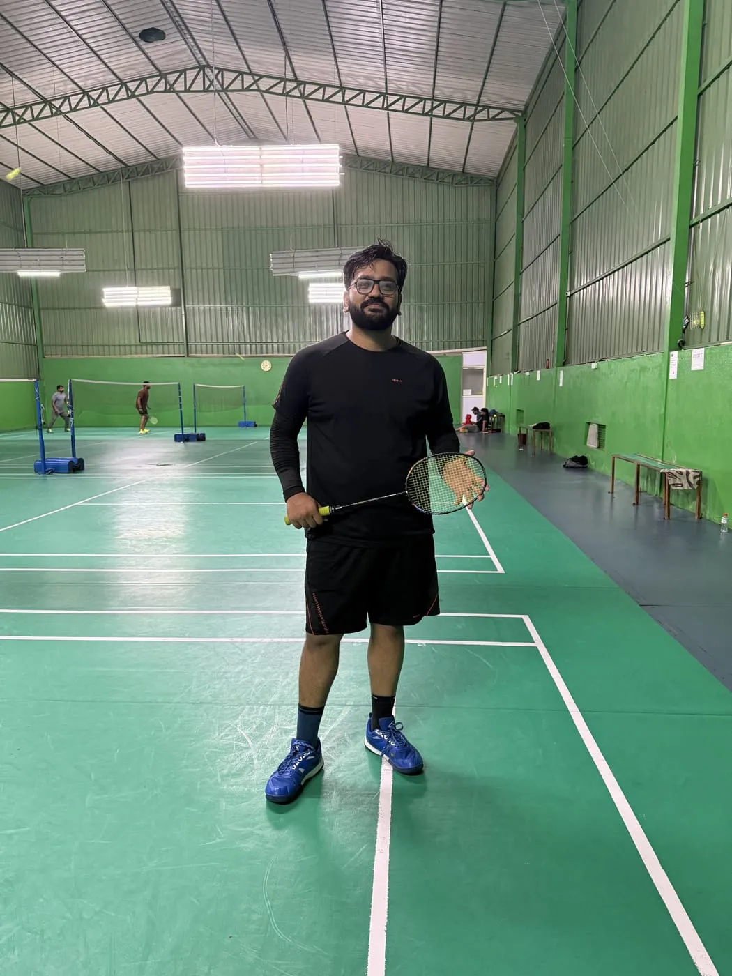 Shishir holding a badminton racquet on an indoor court