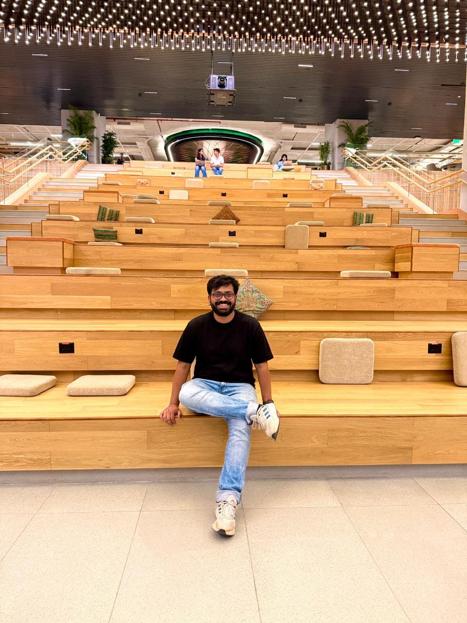 Shishir sitting in a large wooden amphitheatre at a startup workspace